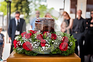 Funerary urn with ashes of dead and flowers at funeral