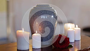 Funerary urn and candles on table burning indoors