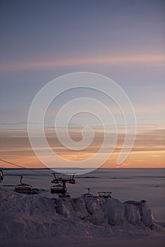 Funicular lifts/cable railway lifts. Pink sunset on top of the mountain. Snow all around, skiing resort beauty.