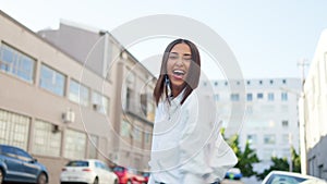 Funky and carefree young woman dancing and looking excited in the city. Happy and positive latino female feeling