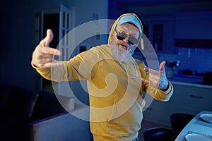 Funky senior man in modern casual clothes dancing for camera