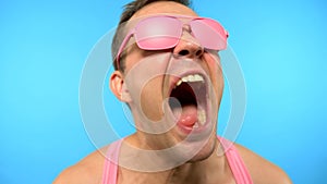 Funky stylish handsome guy in pink sunglasses.  man freak screaming .