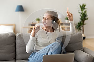 Funky teen girl singing song listening to music in headphones