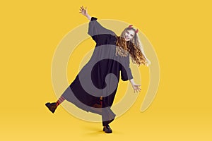 Funky woman in halloween costume, terrifying makeup, red devil horns dancing on yellow background.