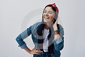 Funky young woman in bandana looking at camera and smiling while standing against grey background