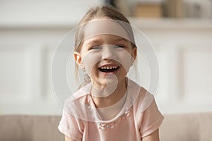 Funny adorable little girl laughing looking at camera, headshot portrait