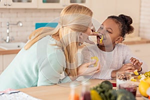 Funny African-American girl laughing while cooking with mother