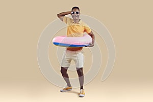 Funny african american man having fun with inflatable circle for swimming at waist.