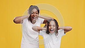 Funny african american mother with her daughter looking surprised, screaming together in amazement and touching heads