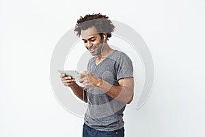 Funny african man in headphones smiling laughing looking at tablet over white background.