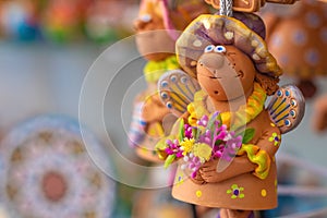 Funny angel with flowers. Simple clay toys in the market.