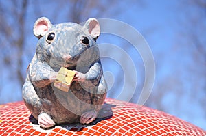 Funny artificial mouse with cheese sitting on the roof