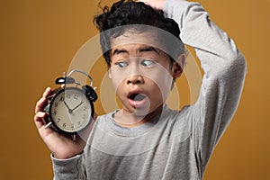 Funny Asian boy awake and shocked because it is too late, young student boy worried to see clock