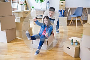 Funny asian couple having fun, riding inside cardboard box smiling happy, very excited moving to a new house