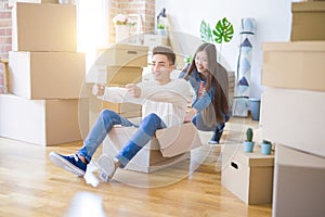 Funny asian couple having fun, riding inside cardboard box smiling happy, very excited moving to a new house