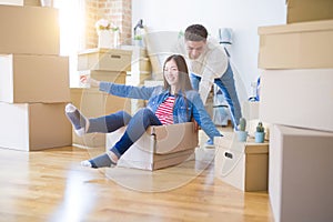 Funny asian couple having fun, riding inside cardboard box smiling happy, very excited moving to a new house
