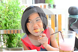 Funny Asian girl eating tasty bread