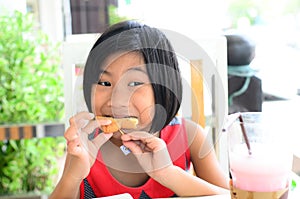 Funny Asian girl eating tasty bread