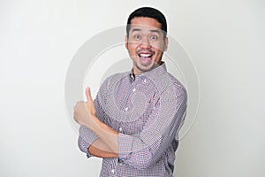 Funny Asian man showing excited face expression while giving thumb up