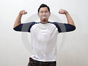 Funny Asian man shows double biceps pose pretending to be a strong person physically and mentally, showing self confidence