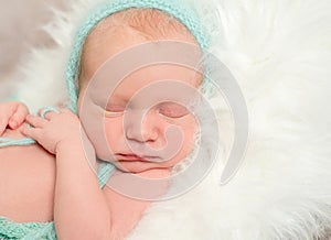 Funny asleep baby face in hat, closeup