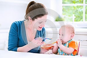 Funny baby boy eating his first solid food