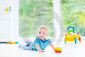 Funny baby boy playing with colorful ball and toy car