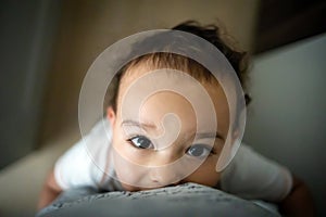 Funny baby boy playing with mom. Toddler keeps moms legs and looking to her