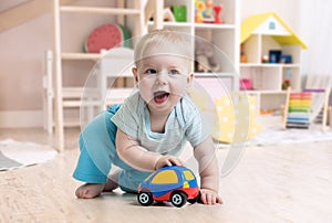 Funny baby boy playing toy in nursery photo