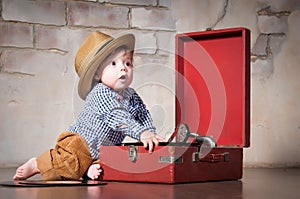 Funny baby boy in retro hat with vinyl record and gramophone