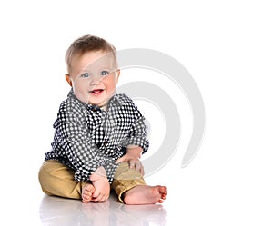 Funny baby boy sitting barefoot in a checkered shirt and pants.