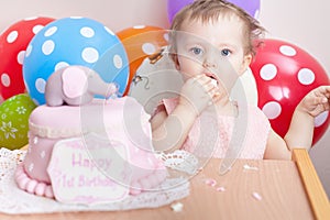 Funny baby celebrating first birthday and eating cake.