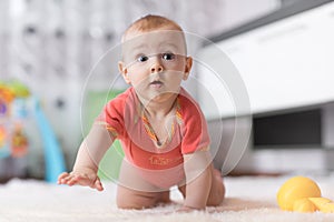 Funny baby crawling on the floor in nursery room