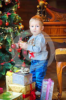 Funny baby decorates the Christmas tree with balls