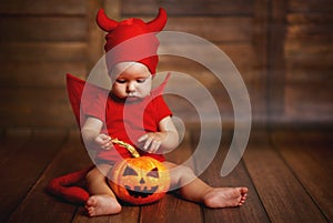 Funny baby in devil halloween costume with pumpkin