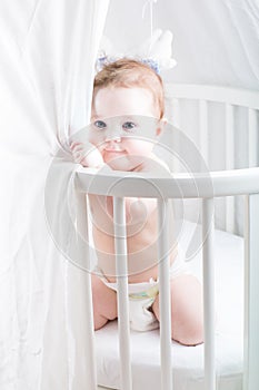 Funny baby in a diaper playing in its crib