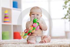 Funny baby in diaper sits on carpet and plays with toy at home. Shallow depth of field.