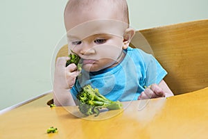 Funny baby eating broccoli