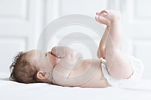Funny baby girl in a diaper on a white blanket