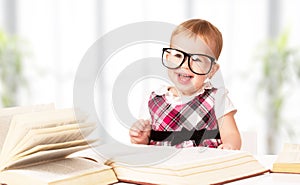 Funny baby girl in glasses reading a book