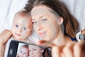 Funny baby girl with mom make selfie on mobile phone photo