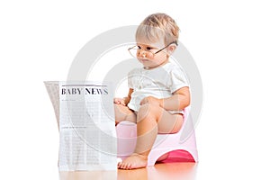 Funny baby girl reading newspaper on chamberpot