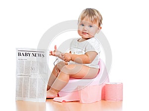 Funny baby girl reading newspaper on chamberpot
