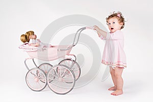 Funny baby girl walking with a doll stroller