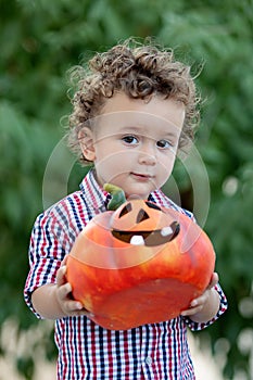 Funny baby holding a big pumpkin