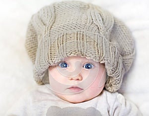 Funny baby in a huge knitted hat