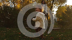 Funny baby playing with mom on the lawn. baby runs on lawn under the supervision of his mother. little daughter playing