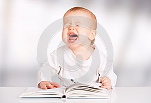 Funny baby reading a book and cries