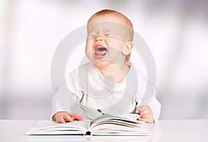 Funny baby reading a book and cries photo