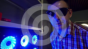 Funny bearded guy with sunglasses is standing next to blue illuminated coolers